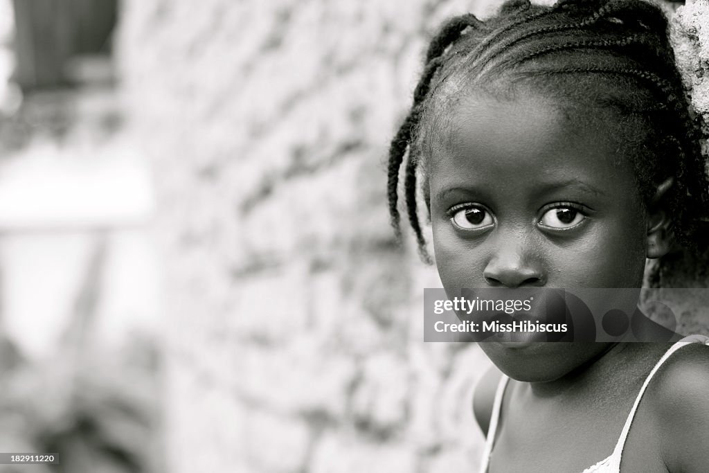 African girl standing against a brick wall