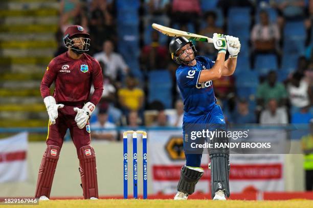 Jos Buttler of England hits 6 as Shai Hope of the West Indies looks on during the 2nd ODI match between the West Indies and England at Vivian...