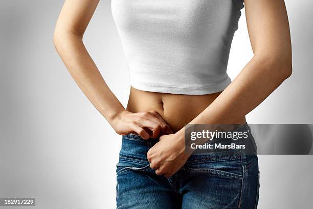 young woman buttoning jeans - dieting concept - form fitted stock pictures, royalty-free photos & images