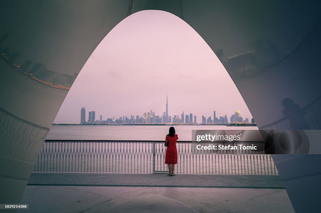 Captivating dusk: Woman admiring Dubai skyline from Creek Harbour
