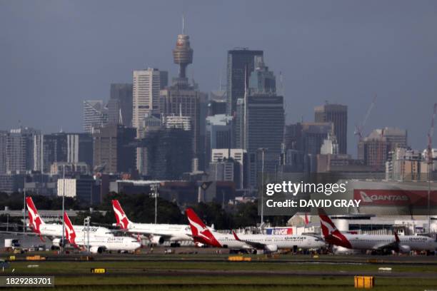 This picture taken on December 6, 2023 shows the Sydney central business district behind Qantas Airways passenger aircraft parked at the Sydney...