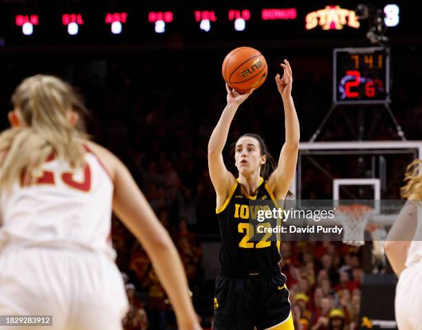 Caitlin Clark of the Iowa Hawkeyes takes a three-point shot against the Iowa State Cyclones defends in the first half at Hilton Coliseum on December...