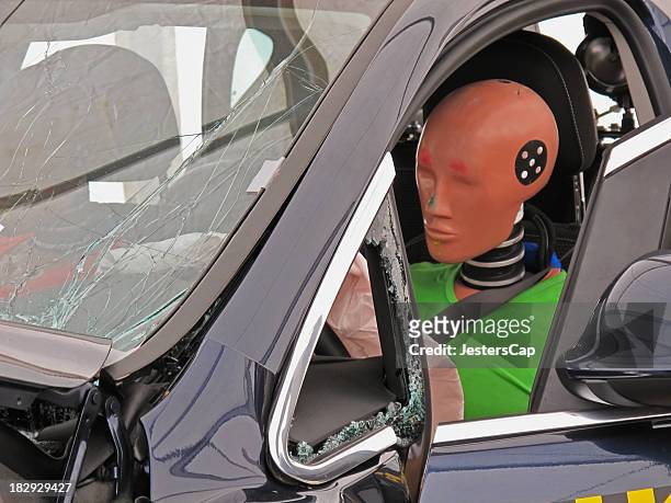 driver's side view of a car with a crash dummy at the wheel - crash test dummy stockfoto's en -beelden