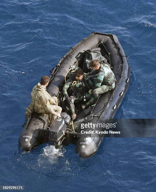 Photo taken from a Kyodo News helicopter on Dec. 6 shows U.S. Military personnel on an inflatable boat as search efforts continue in waters around...