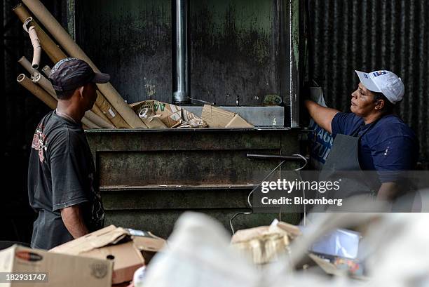 Workers place cardboard to be pressed for recycling into a machine at the COOPERVIVA garbage sorting facility in Rio Claro, Brazil , on Tuesday, Oct....