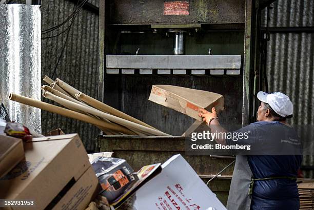Worker throws cardboard to be pressed for recycling into a machine at the COOPERVIVA garbage sorting facility in Rio Claro, Brazil , on Tuesday, Oct....