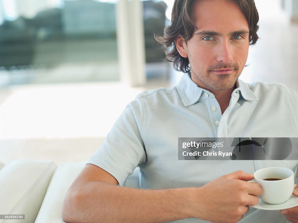 Man on sofa smiling with cup of coffee