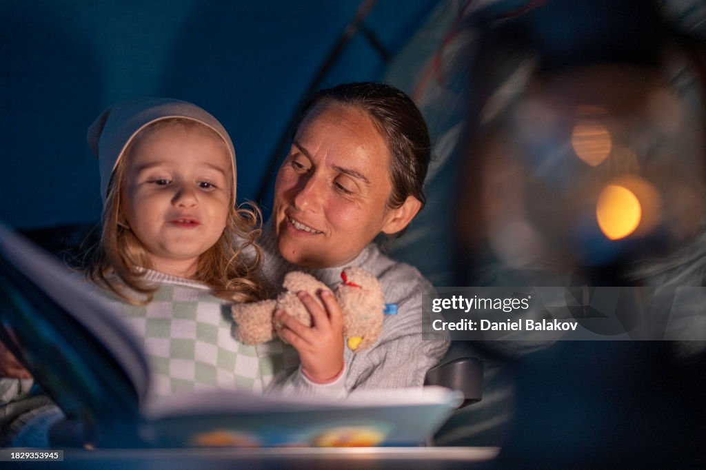 Camping familial au bord du lac. Histoire à l’heure du coucher avec maman dans la tente. espace de copie