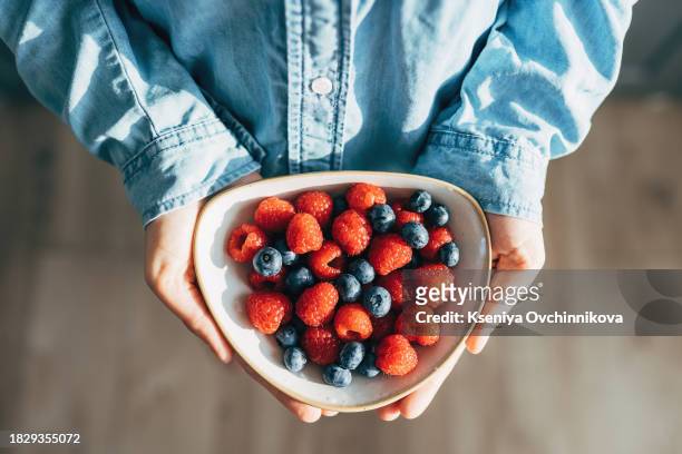 a woman holds a plate of fruits and berries in her hands - blue bowl fotografías e imágenes de stock