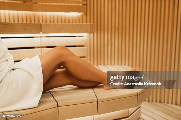 long legged woman wrapped in white towel in a traditional sauna. - cipresso stock-fotos und bilder