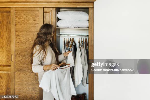 cute young woman selecting clothes from her wardrobe for work or walk. - cipresso stock-fotos und bilder