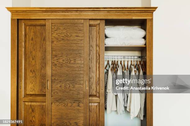 brown wooden wardrobe with clothes and pillows inside. - cipresso stock-fotos und bilder