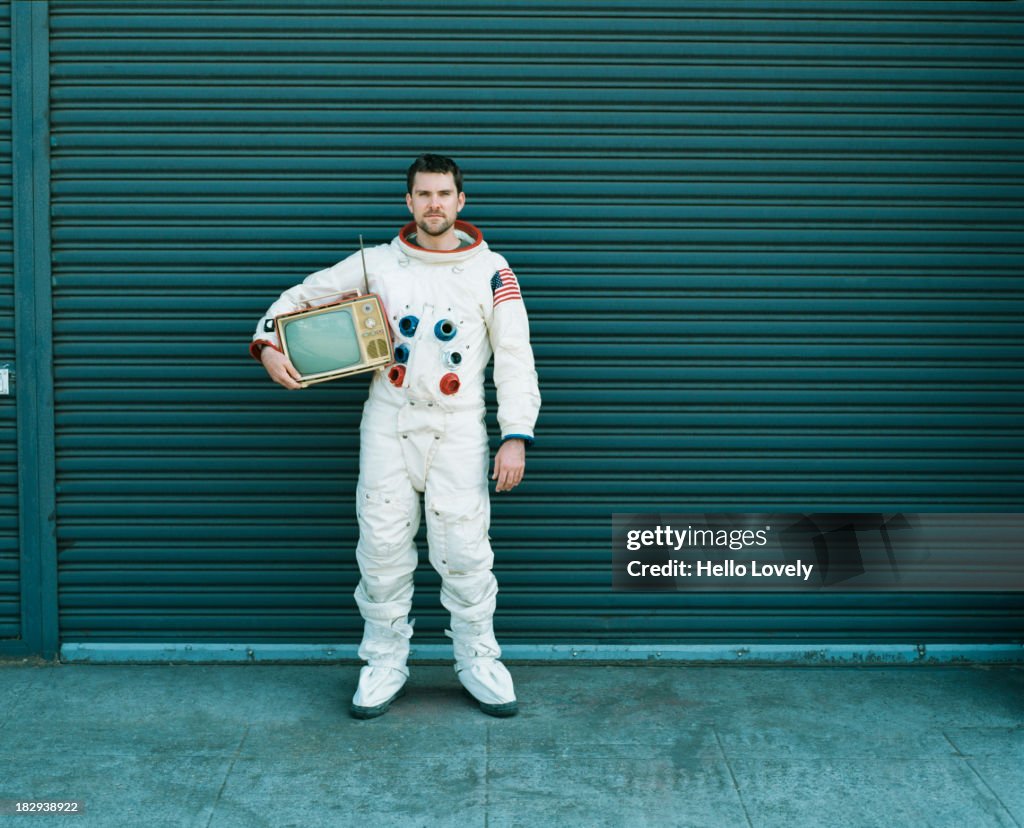 Astronaut carrying television on city street