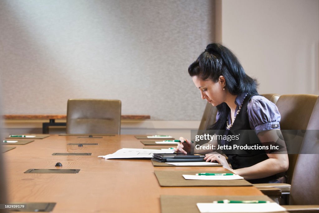 Mixed race businesswoman working at meeting table