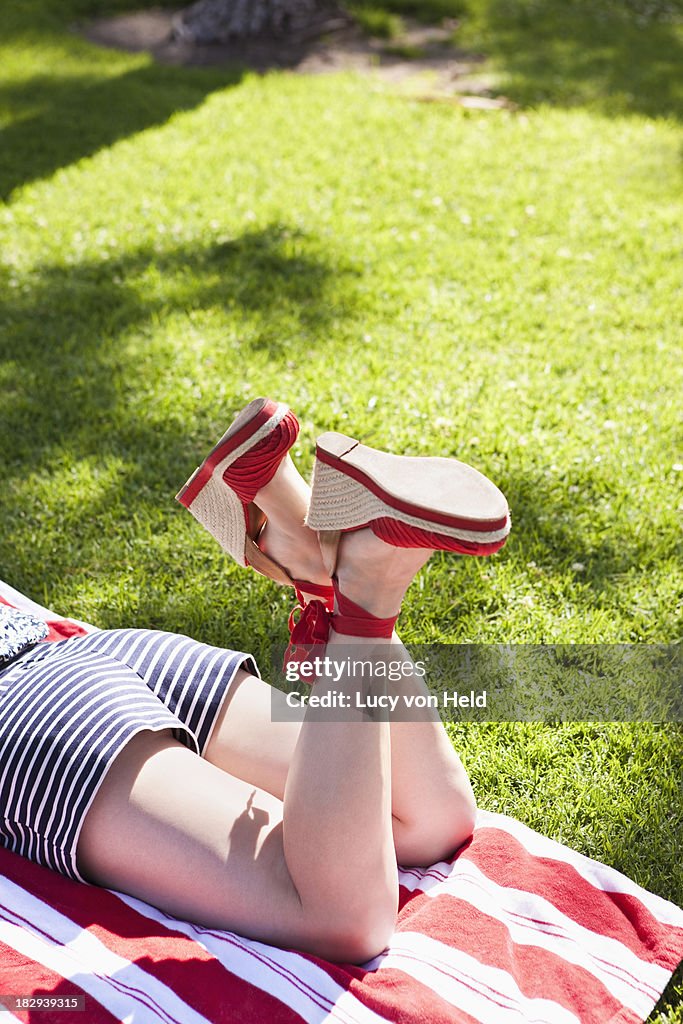 Caucasian woman in heels sunbathing in grass