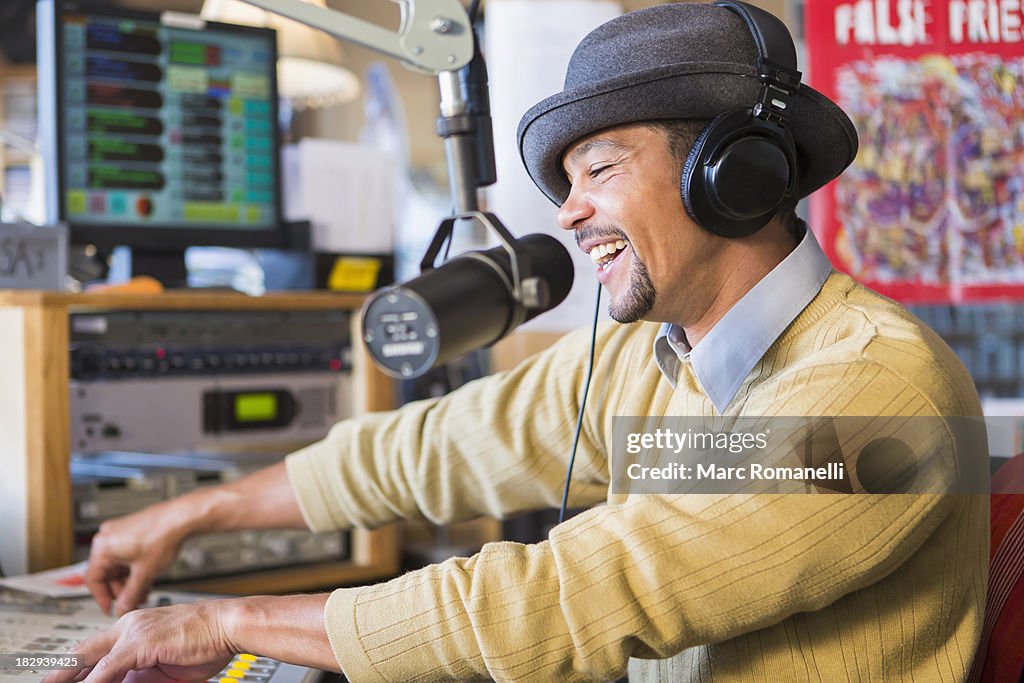 Mixed race disc jockey using turntable in studio