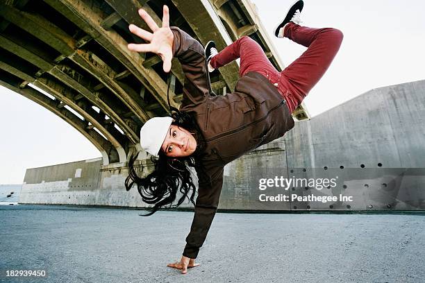 hispanic woman break dancing under overpass - handstand photos et images de collection