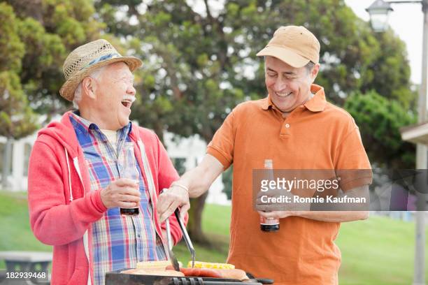older men grilling food together outdoors - beer bottle mouth stock pictures, royalty-free photos & images