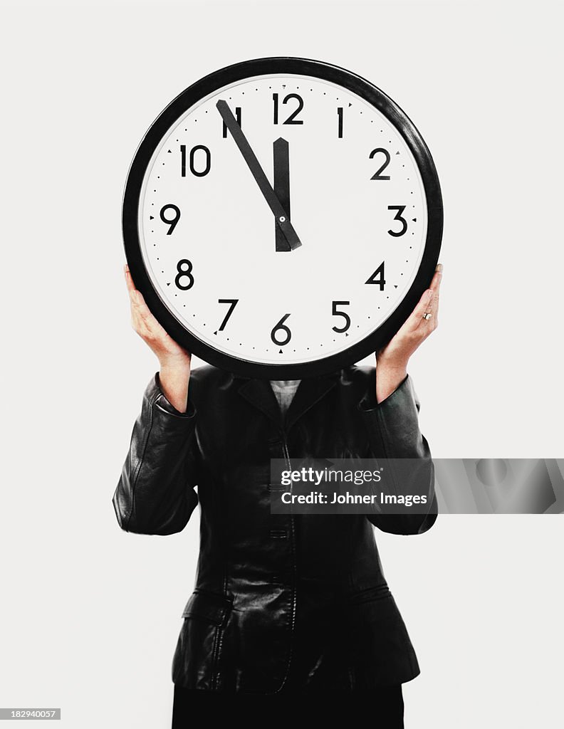 Studio shot of woman holding large clock