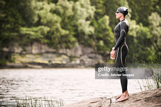 woman in wetsuit standing on beach - wetsuit stock pictures, royalty-free photos & images