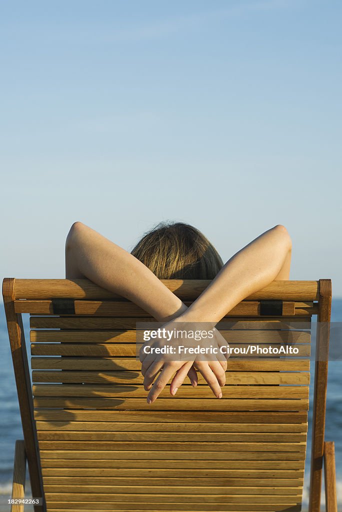 Woman relaxing in lounge chair, rear view