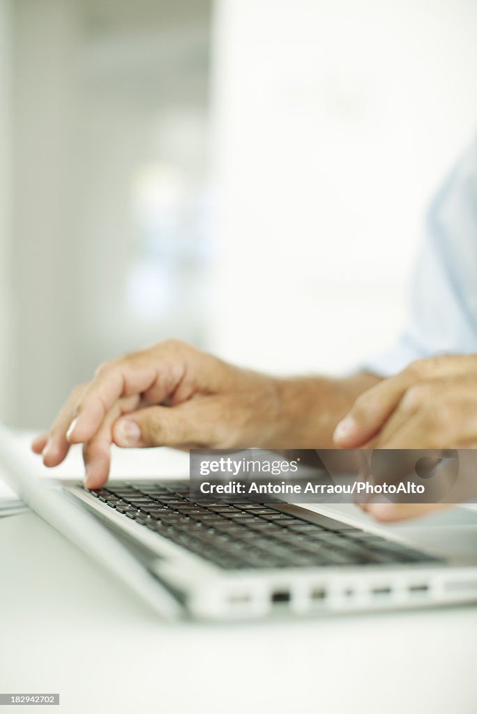 Man typing on laptop computer, cropped