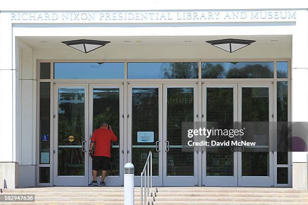 Man peers through the locked front doors of the Richard Nixon Presidential Library and Museum on October 2, 2013 in Yorba Linda, California. The...