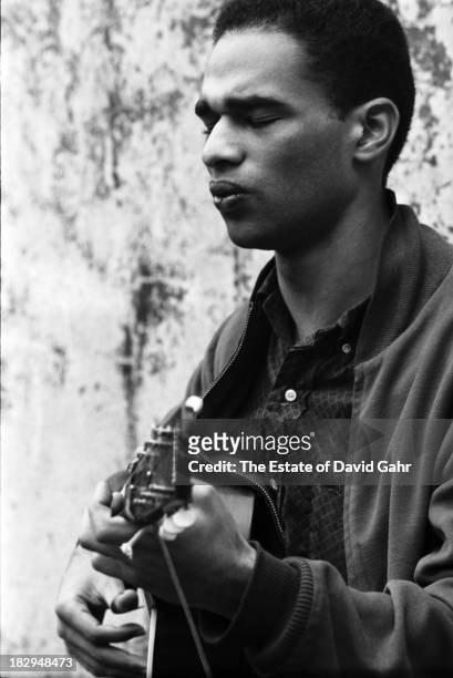 Greenwich Village-based folk and blues singer, civil rights activist, and writer Bill McAdoo poses for a portrait with his guitar in May 1960 in New...