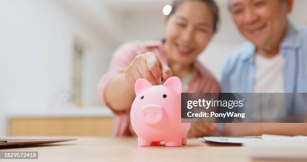 saving money concept - couple saving piggy bank stock pictures, royalty-free photos & images