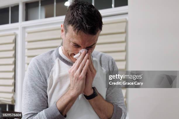 man with flu blows his nose - sinusitis stock-fotos und bilder