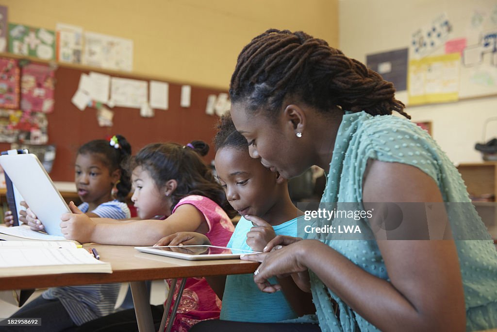 Teacher helping student with digital tablet