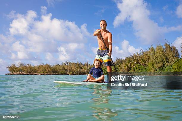 father and son on paddle board together in ocean - paddle board men imagens e fotografias de stock