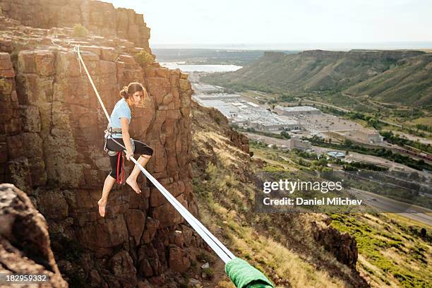 girl sitting on a high slack line over a town. - rope walking stock pictures, royalty-free photos & images