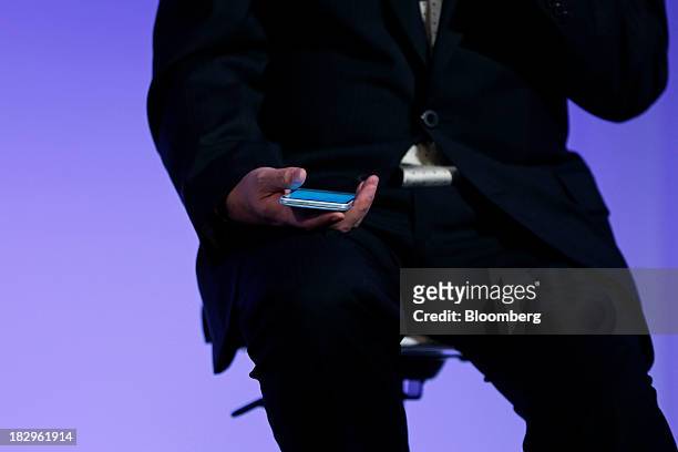 Takashi Tanaka, president of KDDI Corp., holds the company's "au" brand smartphone, the Isai LGL22 manufactured by LG Electronics Inc., during a...