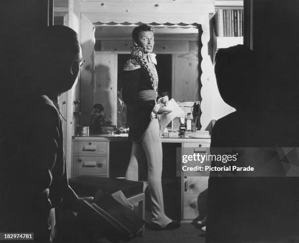 American actor and singer Frank Sinatra talking to Bobby Burns , manager of Tommy Dorsey's band, and publicist Jack Keller, in a dressing room, 1948....