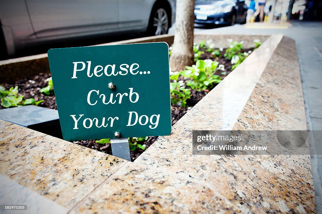 'Curb Your Dog' sign outside city apartment