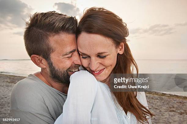 young couple by the sea, smiling - 40s couple stockfoto's en -beelden