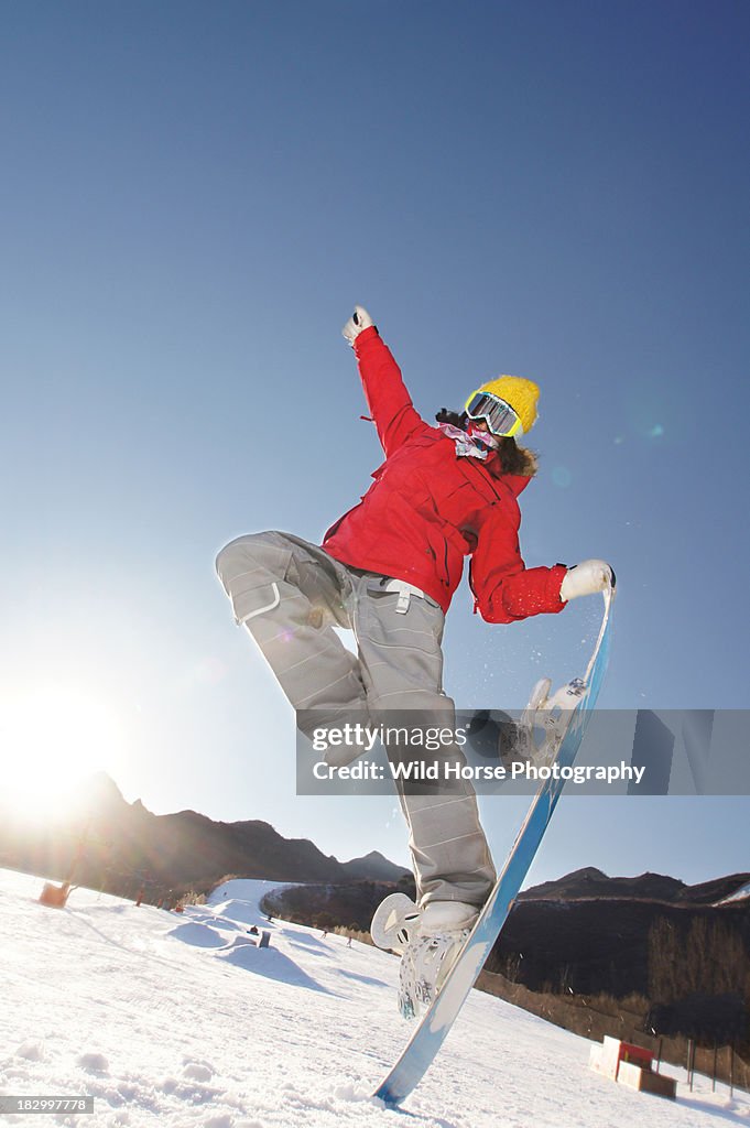 Girl showing trick one foot standing on snowboard