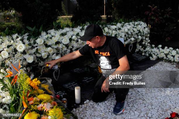 Faithful devotee of Pablo Escobar, Miguel Ángel Cardona pours beer over Pablo Escobar's grave at Jardines Montesacro cementery during 30th...