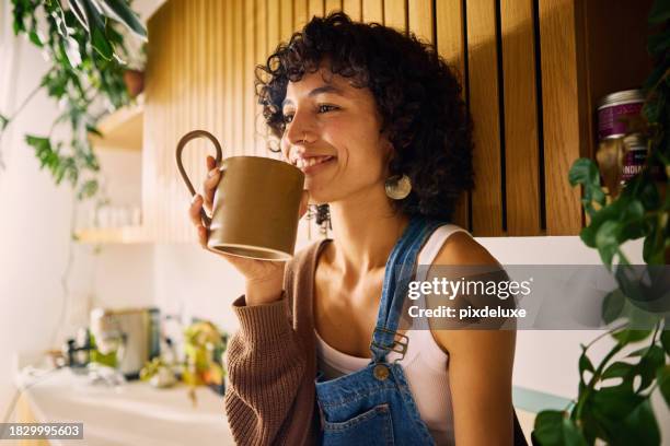 content woman savoring the aroma of her morning coffee in a well-lit kitchen with modern wooden accents and lush houseplants, embracing a moment of serenity, symbolizing mindfulness and the joy of simple pleasures in everyday life - coffee bildbanksfoton och bilder