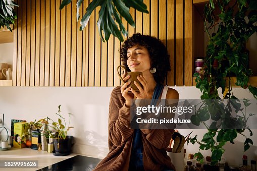 Content Woman Savoring The Aroma Of Her Morning Coffee In A Well-Lit Kitchen With Modern Wooden Accents And Lush Houseplants, Embracing A Moment Of Serenity, Symbolizing Mindfulness And The Joy Of Simple Pleasures In Everyday Life Content Woman Savoring The Aroma Of Her Morning Coffee In A Well-Lit Kitchen With Modern Wooden Accents And Lush Houseplants, Embracing A Moment Of Serenity, Symbolizing Mindfulness And The Joy Of Simple Pleasures In Everyday Life