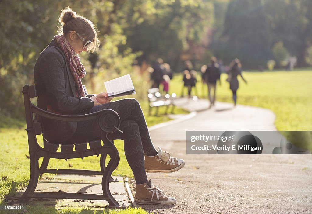 Woman sat on bench reading a book