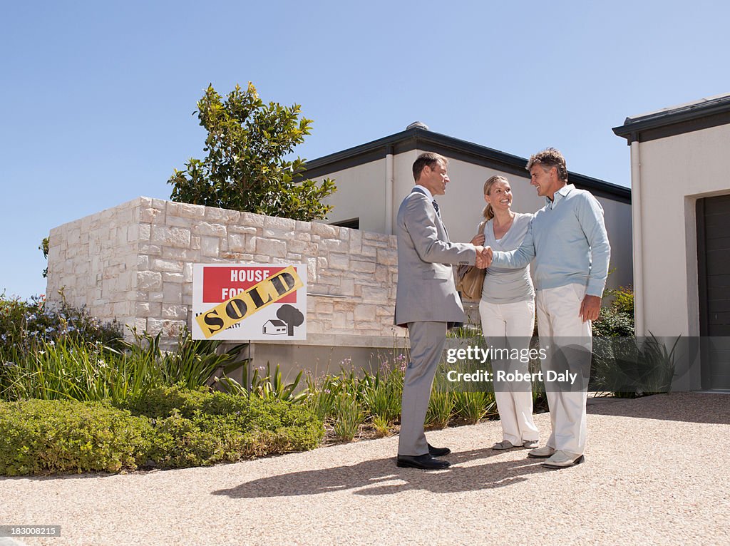 Real estate agent shaking hands with couple at new home
