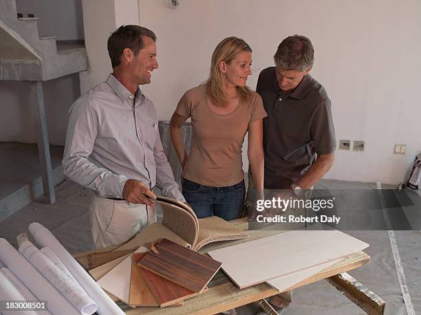 interior designer talking with couple in new home - real estate developer stock pictures, royalty-free photos & images