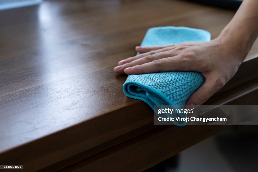 A hand using a cloth to clean the table.
