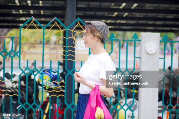 walking thai transgender with cap and shopping bag - kathoey stock pictures, royalty-free photos & images