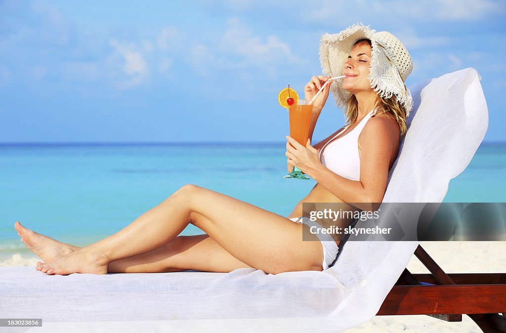 Beautiful woman enjoying at the sun and drink cocktail.