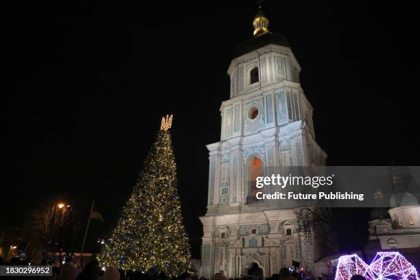 The main Christmas tree of Ukraine crowned with the tryzub sparkles outside the Bell Tower of Saint Sophia Cathedral during the lighting ceremony...