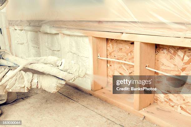 construction worker spraying expandable foam insulation between wall studs - isolatiemateriaal stockfoto's en -beelden