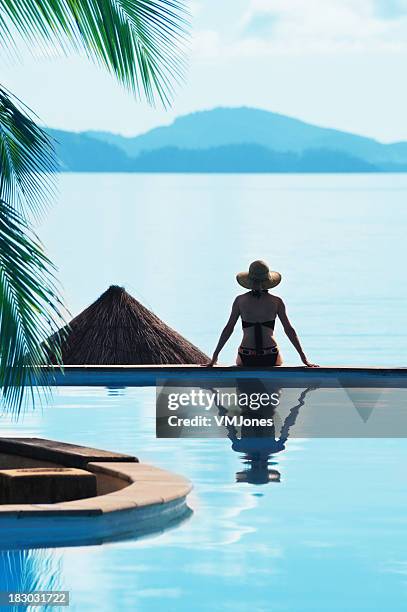 woman sitting by a pool tropical setting - hamilton island stockfoto's en -beelden